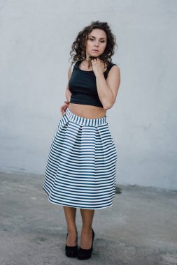 Uzun dalgalı saçlı güzel seksi genç esmer kız ince ince şekil ve oldukça uzun soyulmuş bir etek ve siyah bluz, yüksek topuklu giyiyor makyaj yüz. Rahat tarzı sokakta yürümek