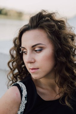 Uzun dalgalı saçlı güzel seksi genç esmer kız ince ince şekil ve oldukça uzun soyulmuş bir etek ve siyah bluz, yüksek topuklu giyiyor makyaj yüz. Rahat tarzı sokakta yürümek