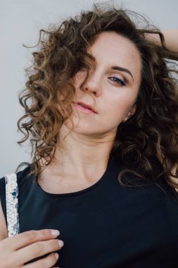 Uzun dalgalı saçlı güzel seksi genç esmer kız ince ince şekil ve oldukça uzun soyulmuş bir etek ve siyah bluz, yüksek topuklu giyiyor makyaj yüz. Rahat tarzı sokakta yürümek