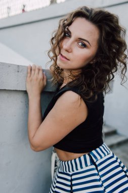 Uzun dalgalı saçlı güzel seksi genç esmer kız ince ince şekil ve oldukça uzun soyulmuş bir etek ve siyah bluz, yüksek topuklu giyiyor makyaj yüz. Rahat tarzı sokakta yürümek