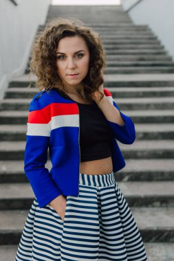 Uzun dalgalı saçlı güzel seksi genç esmer kız ince ince şekil ve oldukça uzun soyulmuş bir etek ve siyah bluz, yüksek topuklu giyiyor makyaj yüz. Rahat tarzı sokakta yürümek