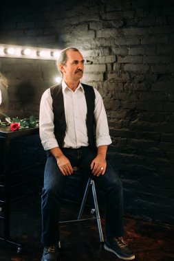 Yakışıklı orta yaşlı adam beyaz gömlek ve siyah yelek giymiş. Siyah arka plan.