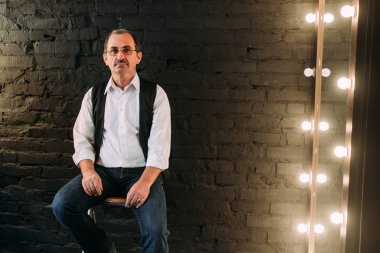 Yakışıklı orta yaşlı adam beyaz gömlek ve siyah yelek giymiş. Siyah arka plan.