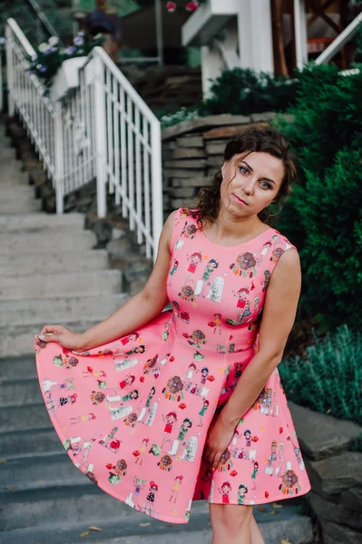 Menina morena bonita posando em vestido rosa fora perto de plantas tropicais — Fotografia de Stock