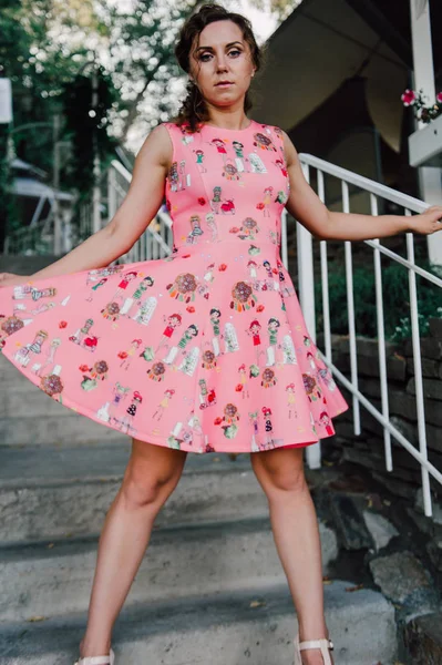 Menina morena bonita posando em vestido rosa fora perto de plantas tropicais — Fotografia de Stock