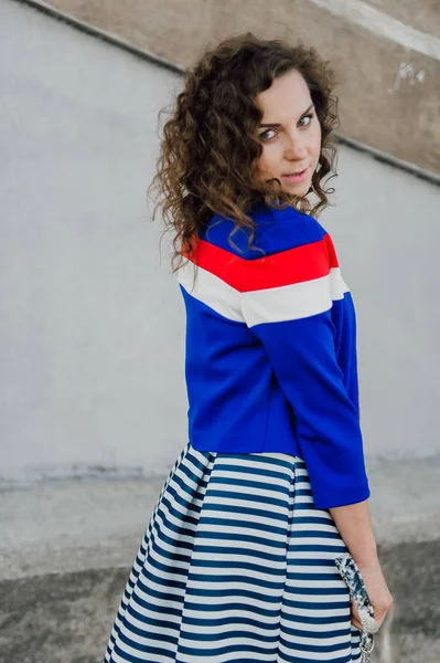 Mooie sexy jonge brunette meisje met lang golvend haar slanke figuur dun en mooi gezicht make-up dragen van een lange gestripte rok en zwarte top, hoge hakken. Lopen op straat in casual stijl — Stockfoto