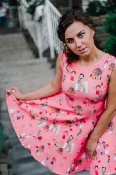 열 대 식물 근처 밖에 서 분홍색 드레스를 입고 포즈를 취하는 아름 다운 갈색 머리 소녀 — 스톡 사진