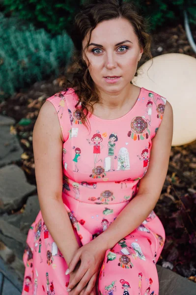 Menina morena bonita posando em vestido rosa fora perto de plantas tropicais — Fotografia de Stock