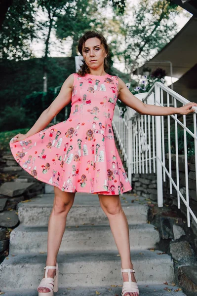 Hermosa chica morena posando en vestido rosa afuera cerca de plantas tropicales — Foto de Stock