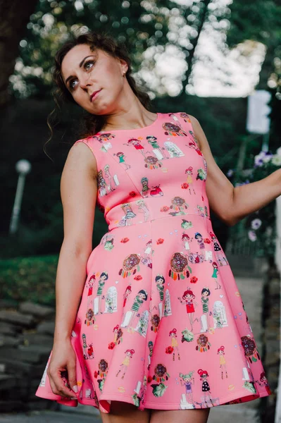 Mooie brunette meisje poseren in roze jurk buiten in de buurt van tropische planten — Stockfoto