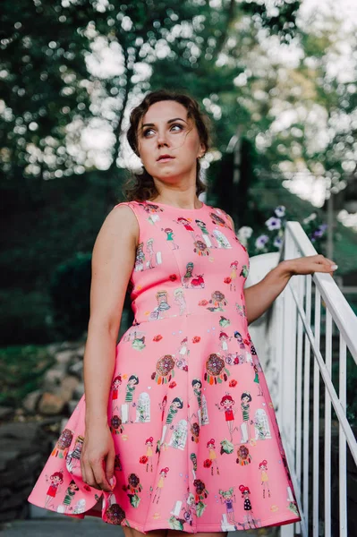 Menina morena bonita posando em vestido rosa fora perto de plantas tropicais — Fotografia de Stock