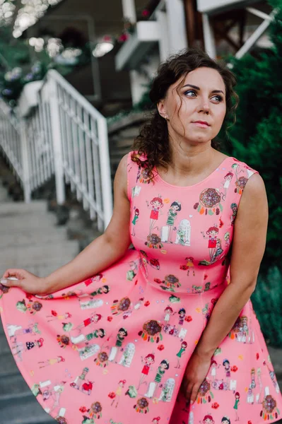 Menina morena bonita posando em vestido rosa fora perto de plantas tropicais — Fotografia de Stock