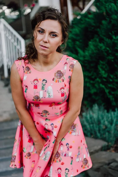 Menina morena bonita posando em vestido rosa fora perto de plantas tropicais — Fotografia de Stock