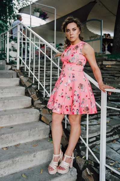 Menina morena bonita posando em vestido rosa fora perto de plantas tropicais — Fotografia de Stock