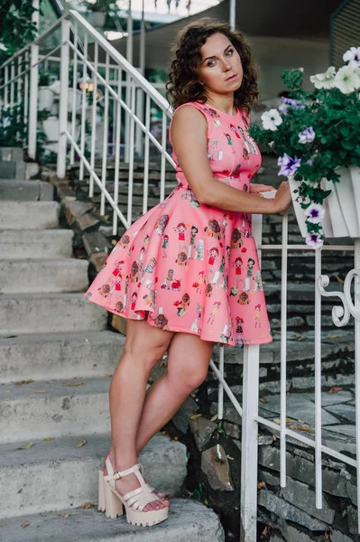 熱帯植物の近くの外のピンクのドレスでポーズ美しいブルネットの少女 — ストック写真