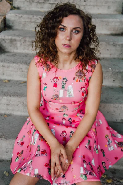 Menina morena bonita posando em vestido rosa fora perto de plantas tropicais — Fotografia de Stock