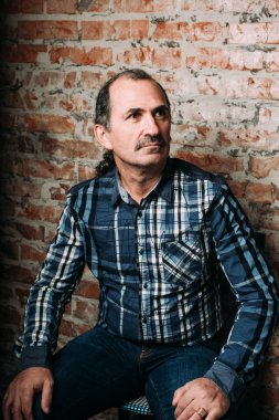 Yakışıklı orta yaşlı adam bir rahat kılığına girmiş. Kırmızı tuğla duvar arka plan.