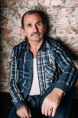 Yakışıklı orta yaşlı adam bir rahat kılığına girmiş. Kırmızı tuğla duvar arka plan.