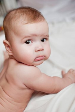 Beyaz yatağa uzanmış güzel bir erkek bebeğin yumuşak bir resmi.