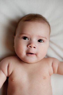 Beyaz yatağa uzanmış güzel bir erkek bebeğin yumuşak bir resmi.