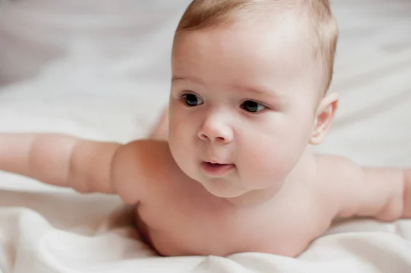 Soft picture of a beautiful baby boy laying on white bedding — Stock Photo, Image