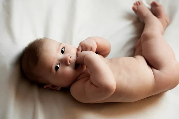 Weiches Bild eines schönen Jungen, der auf weißem Bettzeug liegt — Stockfoto