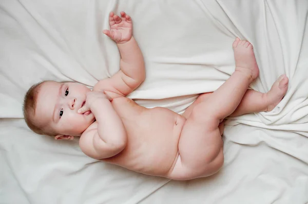 Imagem macia de um lindo menino deitado em roupa de cama branca — Fotografia de Stock
