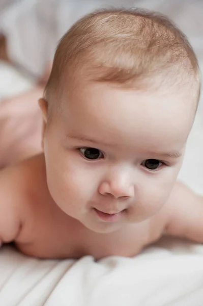 Soft picture of a beautiful baby boy laying on white bedding — Stock Photo, Image