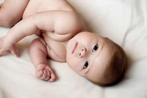 Imagem macia de um lindo menino deitado em roupa de cama branca — Fotografia de Stock