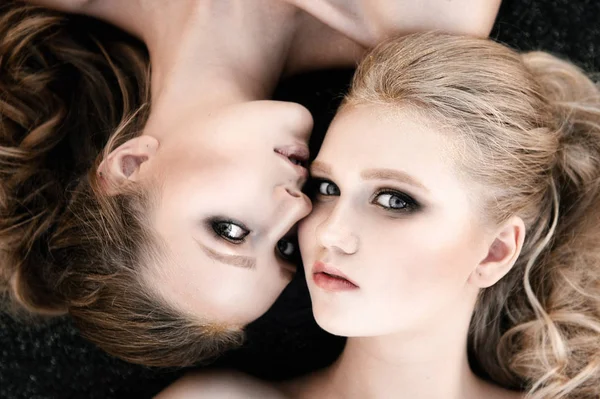 Glamour make-up twee vrouwen met lange haren stijl zittend op straat muur achtergrond in donker. Fashion kleur portret, geretoucheerde foto — Stockfoto