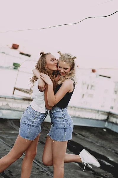 Lifestyle and people concept: Fashion portrait of two stylish girls best friends wearing jeans skirts, outdoors on the roof. Happy summer time for fun. Concept of 90s. Retouched photo — Stock Photo, Image