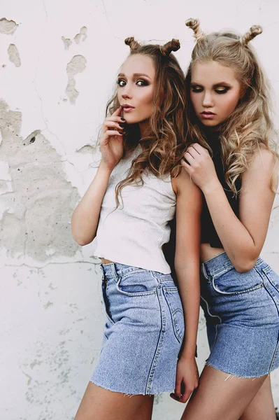 Estilo de vida y el concepto de la gente: Retrato de moda de dos chicas con estilo mejores amigos con faldas vaqueros, al aire libre en el techo. Feliz verano por diversión. Concepto de los 90. Foto retocada — Foto de Stock