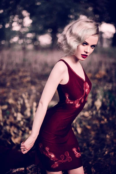 Mulher loira bonita e elegante com lábios vermelhos e ondas de cabelo vestindo vinho camisa vermelha posando na cama ao ar livre outono, estilo vintage retro e moda. Tonificação retocada tiro — Fotografia de Stock