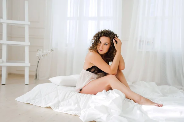 Sexy kobieta w łóżku rano wykazujące jej piękne ciało. Obudzić się z naturalnego światła w jej sypialni i pokryte w pościeli. Retuszować zdjęcia. — Zdjęcie stockowe