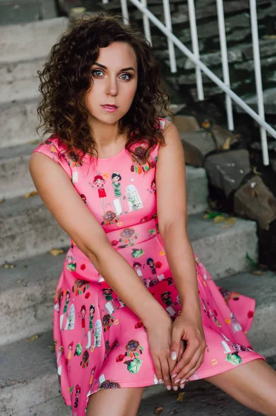 Menina morena bonita posando em vestido rosa fora perto de plantas tropicais — Fotografia de Stock