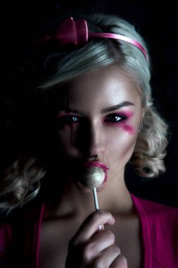 Yaratıcı bebek makyaj ile iki kuyruklu ile güzel sarışın kız: pembe Pembe iskelet elbise yalama lolipop giyen parlak dudaklar. Cadılar Bayramı partisi için. Düzeltisiz görüntü kadar yakın.