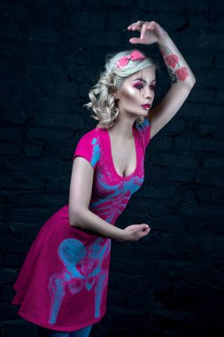 Yaratıcı bebek makyaj ile iki kuyruklu ile güzel sarışın kız: pembe Pembe iskelet elbise giyen parlak dudaklar. Cadılar Bayramı partisi için. Bir bebek gibi poz. Atış, stüdyo düzeltisiz resim.