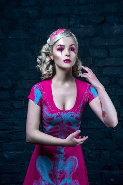 Yaratıcı bebek makyaj ile iki kuyruklu ile güzel sarışın kız: pembe Pembe iskelet elbise giyen parlak dudaklar. Cadılar Bayramı partisi için. Bir bebek gibi poz. Atış, stüdyo düzeltisiz resim.