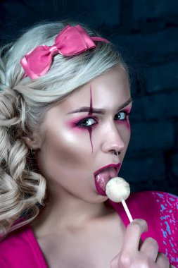 Yaratıcı bebek makyaj ile iki kuyruklu ile güzel sarışın kız: pembe Pembe iskelet elbise yalama lolipop giyen parlak dudaklar. Cadılar Bayramı partisi için. Düzeltisiz görüntü kadar yakın.