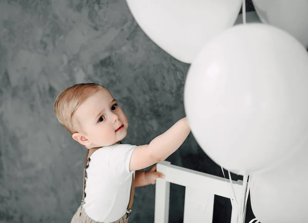 Retrato del adorable niño feliz sonriendo celebrando 1 año de cumpleaños. Un pequeño caballero europeo de un año jugando con globos — Foto de Stock