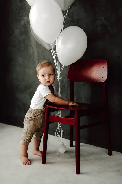 Retrato del adorable niño feliz sonriendo celebrando 1 año de cumpleaños. Un pequeño caballero europeo de un año jugando con globos — Foto de Stock