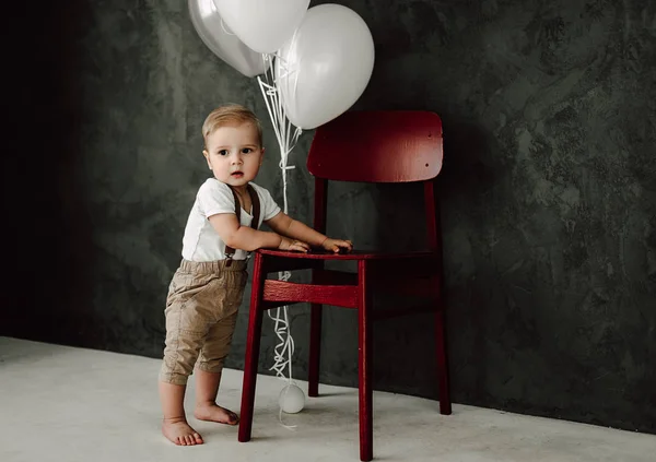 Retrato del adorable niño feliz sonriendo celebrando 1 año de cumpleaños. Un pequeño caballero europeo de un año jugando con globos — Foto de Stock