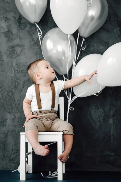 Portret piękny mały chłopiec szczęśliwy uśmiechający się obchodzi 1 rok urodziny. Rok Europejski mały gentelman siedzi w fotelu i gra z baloons — Zdjęcie stockowe