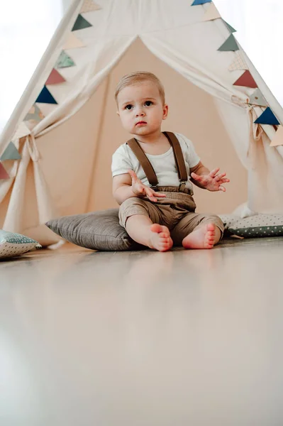 Retrato de adorável menino pequeno feliz sorrindo celebrando 1 ano de aniversário. Um ano de idade europeu pequeno cavalheiro sentado em uma tenda de bebê wigwam — Fotografia de Stock