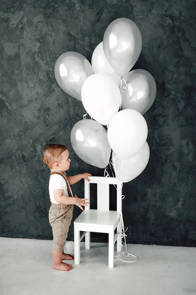 Retrato del adorable niño feliz sonriendo celebrando 1 año de cumpleaños. Un pequeño caballero europeo de un año jugando con globos — Foto de Stock