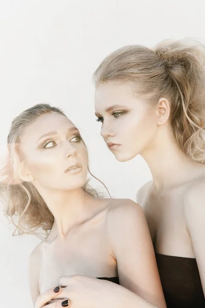 Glamour make-up twee vrouwen met lange haren stijl zittend op straat muur achtergrond in donker. Fashion kleur portret, geretoucheerde foto — Stockfoto