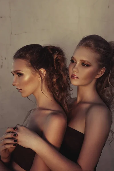魅力化妆两个妇女坐在黑暗中街道墙背景上的长长的头发样式。时尚彩色肖像，处理过的照片 — 图库照片