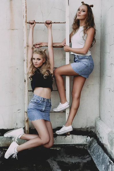 Levensstijl en mensen concept: Fashion Portret van twee stijlvolle meisjes beste vrienden dragen jeans rokken, buiten op het dak. Gelukkig zomertijd voor de lol. Concept van de jaren 90. Geretoucheerde foto — Stockfoto