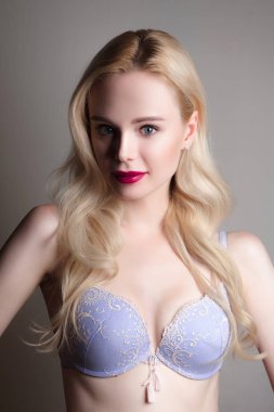 Güzellik modeli kız mükemmel makyaj ile kırmızı dudaklar ve mavi gözleri mavi sütyen giyiyor kameraya bakıyor. Sarışın çekici seksi genç kadın portresi. Güzel kadın yüzü ile temizleyin taze cilt.
