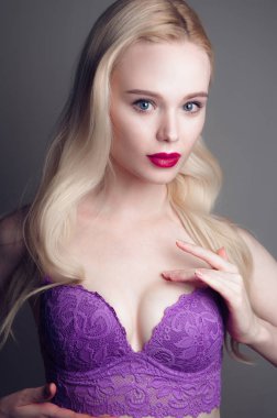 Güzellik modeli kız mükemmel makyaj ile kırmızı dudaklar ve mavi gözleri kırmızı sutyen giyiyor kameraya bakıyor. Sarışın çekici seksi genç kadın portresi. Güzel kadın yüzü ile temizleyin taze sk